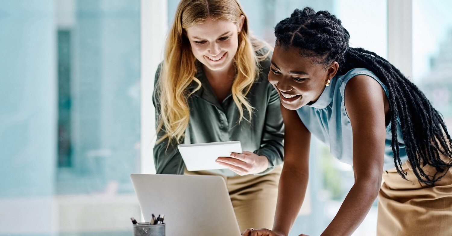 women looking at a laptop, smiling.